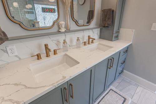 greg papenfus stewart bathroom design blue cabinetry with dual sinks and gold fixtures